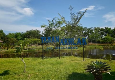 Papan nama Taman AKHLAK di tepi kolam